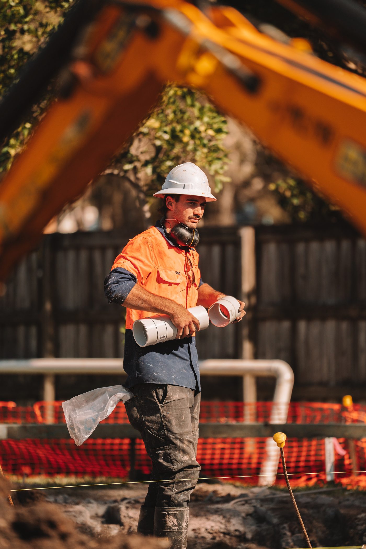 Plumber carrying stormwater pipe across site